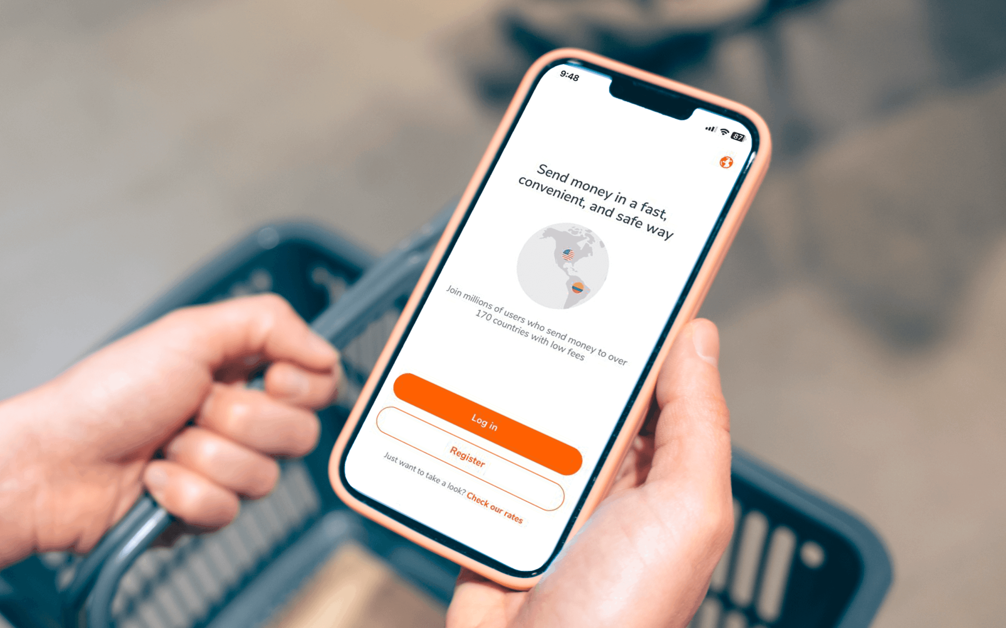 hands holding a shopping basket and a phone open to the Ria Money Transfer app