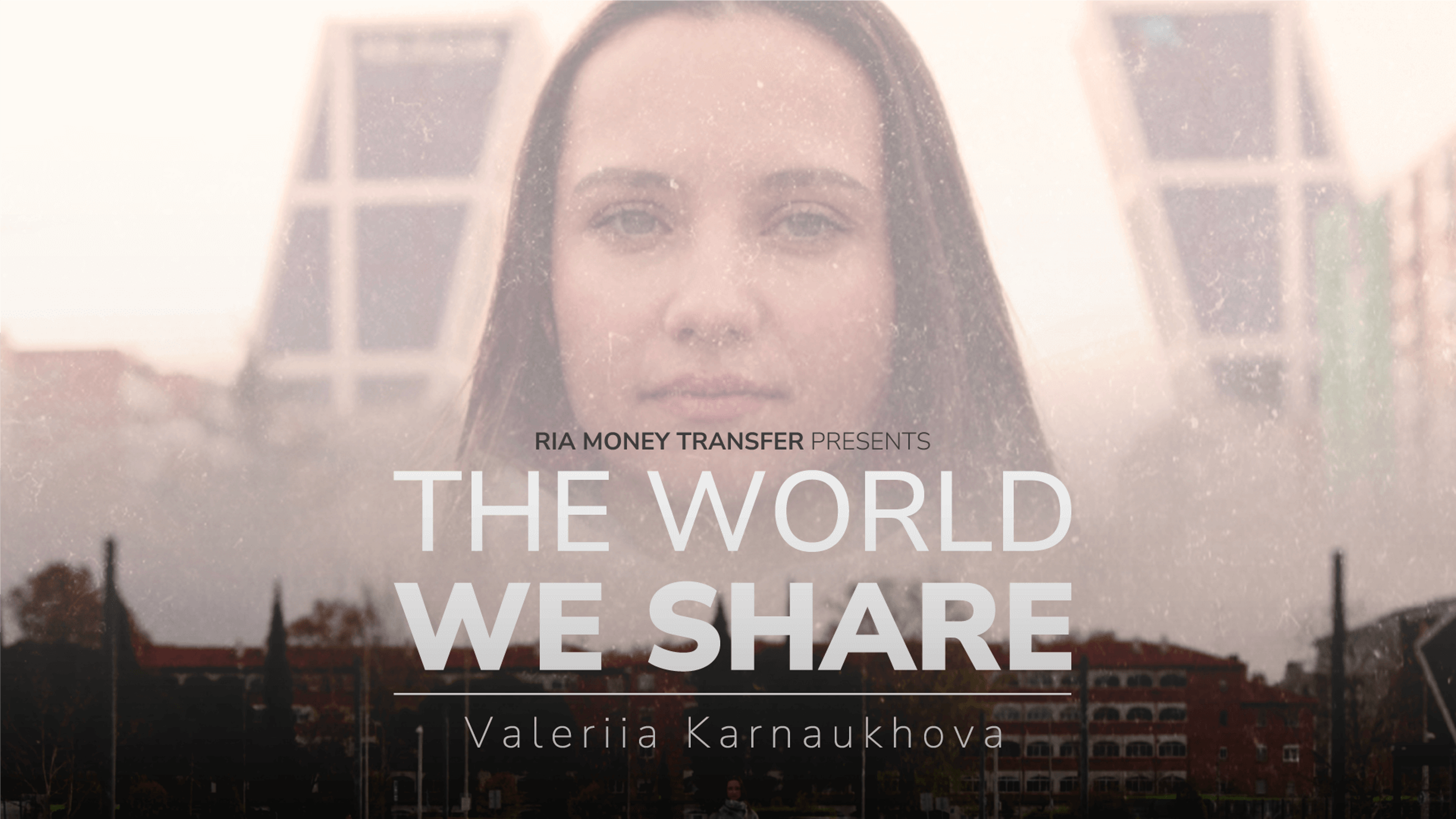 A poster featuring a woman with a serious expression in the center. Text overlaid on the image reads, "RIA Money Transfer Presents The World We Share" with "Valeriia Karnaukhova" written underneath. The backdrop includes modern buildings and a cityscape.