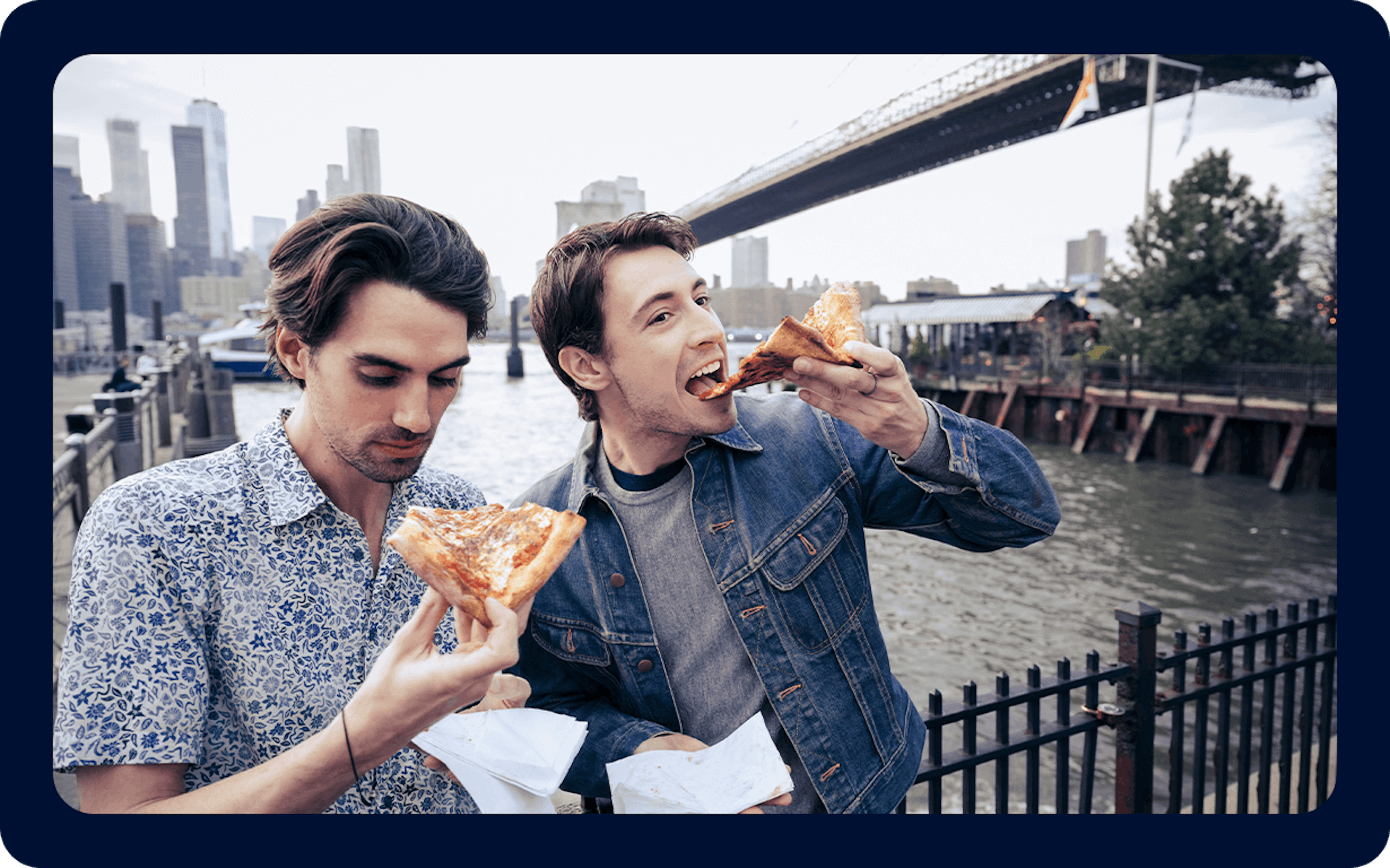 Two men eating pizza in a city in the United States